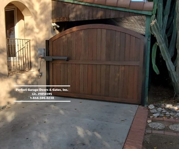 Custom Stained Vertical Wood Swing Driveway Gate with Arch and Overlay Framing